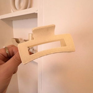 Detail view of a large cream velvet rectangular hair claw clip held by hand