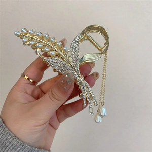 Detail of gold flower hair claw clip with white pearls, rhinestones and tassel pendants