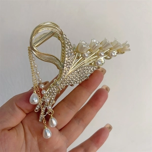 Detailed macro view of golden lily of the valley hair claw clip with pearl tassels