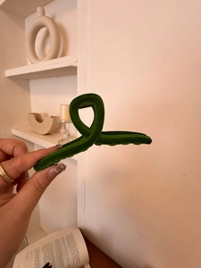 Detail of dark green velvet hair claw clip with twisted ribbon design and matte texture