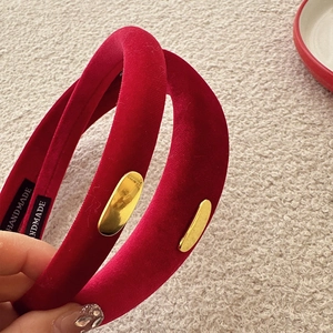 Macro detail of red velvet headband with gold metal accents and handmade inner label
