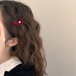 Eleganter roter Samt-Haarclip mit Schleife und Perle, an gewelltem Haar getragen
