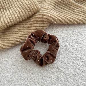 Detail of coffee velvet scrunchie with tiny pearls on soft knit and faux fur background