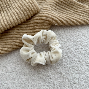 Detailed macro view of cream velvet scrunchie with silver sequins and soft texture
