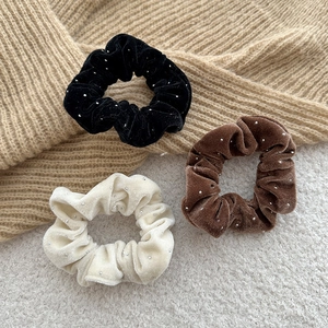 Detail of velvet scrunchies with pearl beads in black, brown, and cream colors