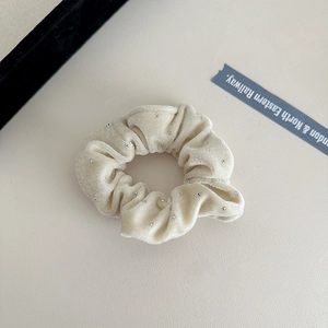Detail of soft beige velvet scrunchie with sparkling rhinestones and ruffled texture