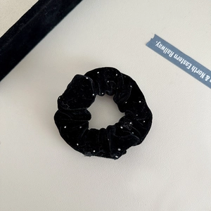 Detail of black velvet scrunchie with sparkling silver dots and soft wrinkled texture