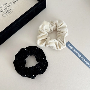 Detail of velvet hair scrunchies with silver studs in black and cream beige set