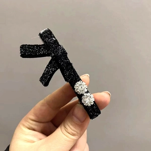 Dettaglio molletta nera a forma di AK-47 con tessuto glitterato e grandi strass