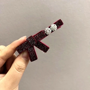 Dettaglio di un fermaglio a fiocco in velluto rosso vino con glitter e cristalli lucenti