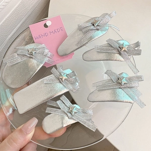 Détail de barrettes argentées faites à la main avec nœuds pailletés et étoiles