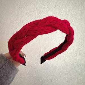 Detail of red knitted braided headband with thick texture and black non-slip lining
