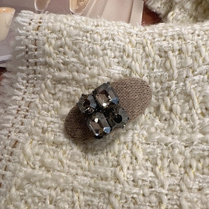 Détail de la pince à cheveux ovale rétro avec strass gris et base texturée en tissu marron