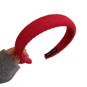 Red ribbed knit headband for women featuring a thick braided wave texture and handmade label