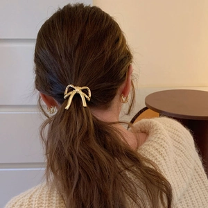 Élastique à cheveux avec nœud en métal doré sur une queue de cheval haute élégante
