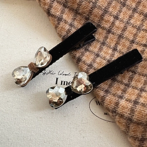 Detail of black velvet hair clips with two large heart-shaped crystals on a warm background