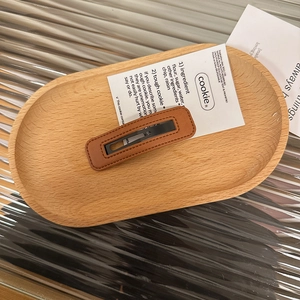 Detail of square brown leather hair clip with fine stitching on a wooden tray