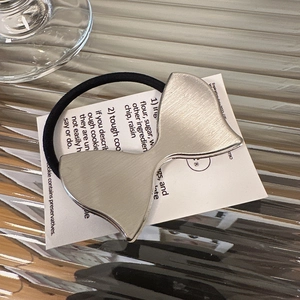 Dettaglio dell'elastico per capelli con fiocco metallico argentato e trama spazzolata
