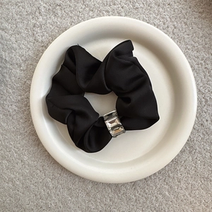Elegant black satin hair scrunchie with rhinestones on a white tray minimalist decor