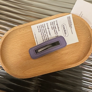 Detail of a dark purple leather square hair clip with premium stitching and BB metal clip