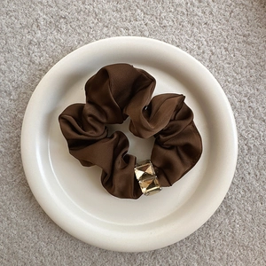Dark brown satin scrunchie with square amber rhinestones on a white ceramic plate