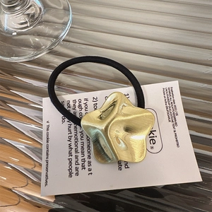 Dettaglio di un elastico per capelli in metallo dorato a forma di stella ondulata