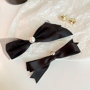 Detail of black bow hair clips with pearls, mesh, and branded silver metal charm