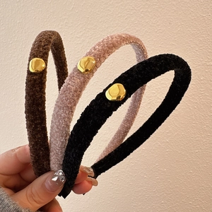 Detailed view of plush velvet headbands in brown, pink, and black with golden metal buckles