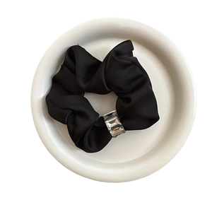 Elegant black satin scrunchie with sparkling rhinestones on a white ceramic plate