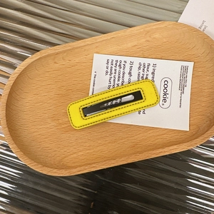 Detail of yellow rectangular leather hair clip showing the fine stitching and metal backing