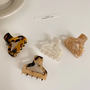 Set of four glossy acetate mini claw clips in leopard and neutral tones on a cream background