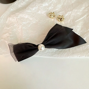 Detailed macro of black layered mesh bow hair clip with a center faux pearl accessory