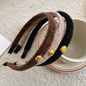 Close-up of fuzzy plush headbands in brown and black with golden bead accents