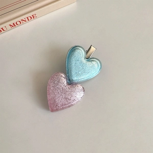 Détail de barrettes coeur rose et bleu avec texture pailletée et pinces crocodile en métal argenté