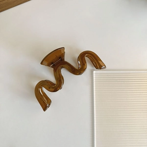 Détail de la pince à cheveux ondulée marron ambre avec finition acrylique brillante