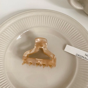 Detail showing high-quality acetate hair claw with marble texture on ceramic tray