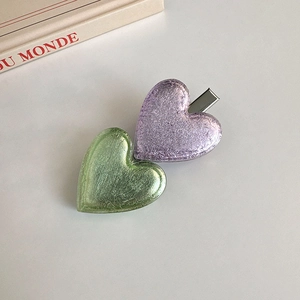 Gros plan sur les barrettes cœur vintage en violet et vert avec texture métallisée