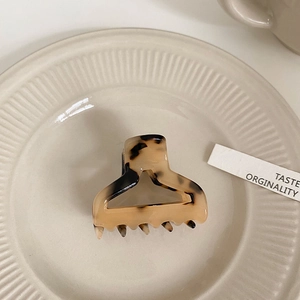 Detail of tortoise shell claw clip on ceramic plate with leopard print and spring mechanism