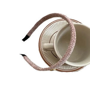 Elegant thin mauve plush headband with gold logo accent on a vintage coffee cup