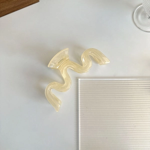Vue détaillée de la pince à cheveux ondulée crème avec finition en résine et ressort