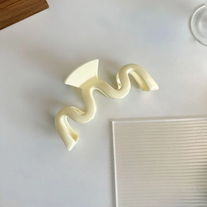 Détail macro de la pince à cheveux ondulée crème avec finition lisse en résine