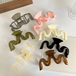 Vue à plat de grandes pinces à cheveux ondulées aux couleurs brillantes sur fond blanc