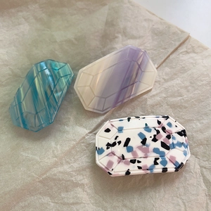 Detailed close-up of octagonal acetate hair clips with blue marble and terrazzo textures