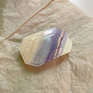 Macro shot of purple and yellow acetate gemstone cut hair clip on vintage paper