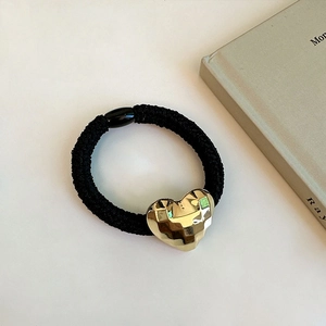 Détail d'un élastique à cheveux noir avec un pendentif en forme de cœur doré facetté