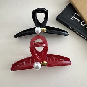 Detail of red and black shark hair clips featuring pearls and golden metal tag decoration