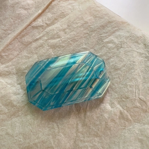 Macro view of blue acetate hair clip with geometric facets and marble texture