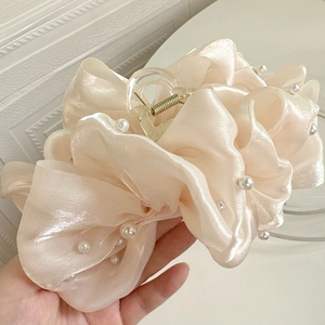 Détail de la pince à cheveux en organza champagne avec perles et design en cœur