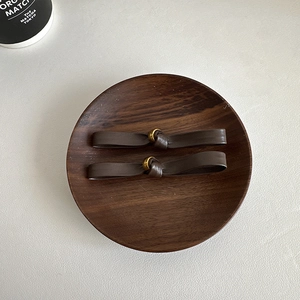 Brown leather bow hair tie set with gold ring detail on a vintage wooden tray