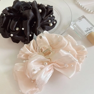Détail de grandes pinces à cheveux en satin noir et rose avec perles élégantes